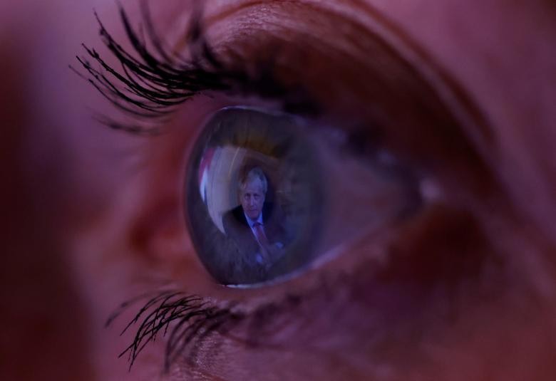 Britain's Prime Minister Boris Johnson is reflected in a woman's eye as she watches his address to the nation following the outbreak of the coronavirus in Manchester, Britain. REUTERS/Phil Noble  